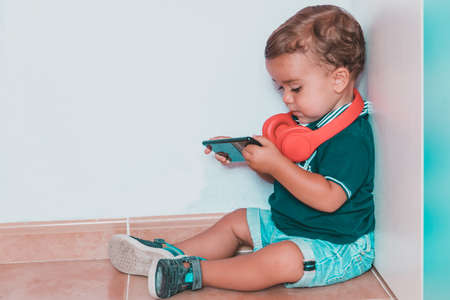 portrait child listening to music with headphones on brick wallの写真素材