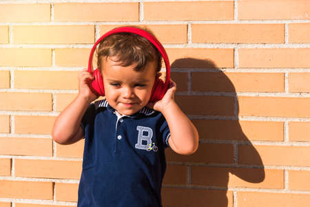 portrait child listening to music with headphones on brick wallの写真素材