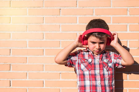 portrait kid listening to music with headphones on brick wallの写真素材