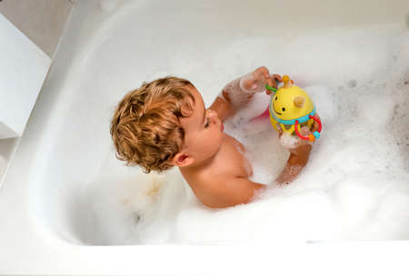 Child bathing in tub at home with foamの写真素材