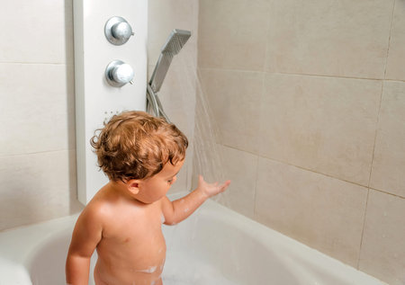 Child bathing in tub at home with foam