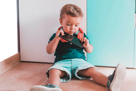 child listening to videos with mobile phone and headset