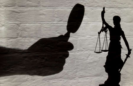 Concept of a magnifying glass looking closely at justice. Shadow on wall.の写真素材