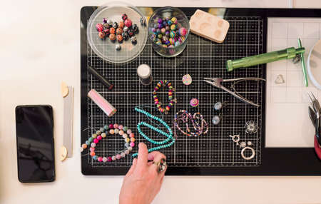 young woman in jewelry workshop writing a message on her cell phoneの写真素材
