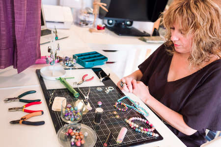 young woman in jewelry workshop writing a message on her cell phoneの写真素材