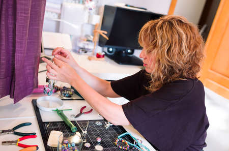 young woman in jewelry workshop writing a message on her cell phoneの写真素材