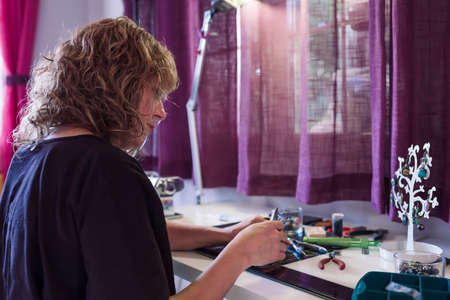 young woman in jewelry workshop writing a message on her cell phoneの写真素材