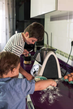 Two children preparing pancakes with a kitchen robot.の写真素材