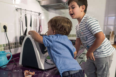 Two children preparing pancakes with a kitchen robot.の写真素材