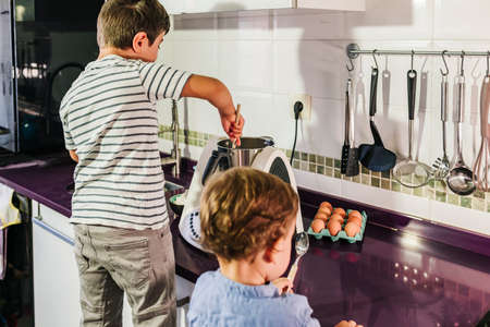 Two children preparing pancakes with a kitchen robot.の写真素材