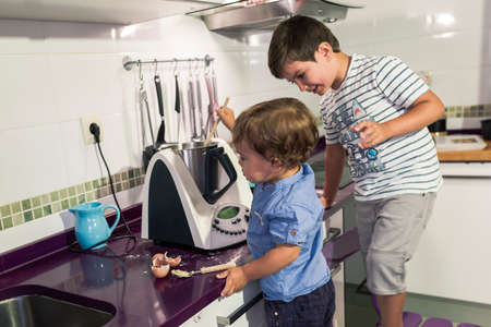 Two children preparing pancakes with a kitchen robot.の写真素材