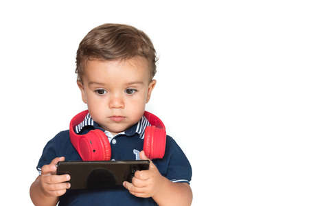 child watching videos on mobile phone with red headphones and dark blue shirtの写真素材