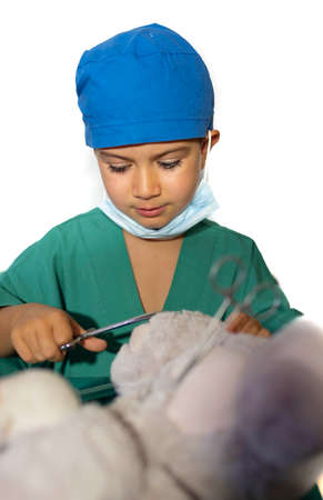 concept of a child's vocation playing doctor-surgeon operating a teddy bear.の写真素材