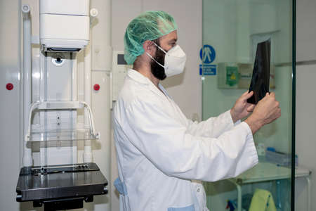 Doctor with mask checking mammography of woman in x-ray room.の写真素材
