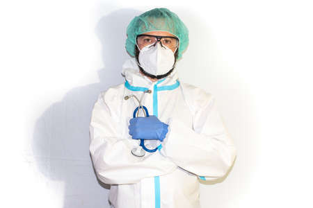 Middle-aged male doctor dressed in protective gear and stethoscope standing on an isolated white background facing the camera. Positive person.の写真素材