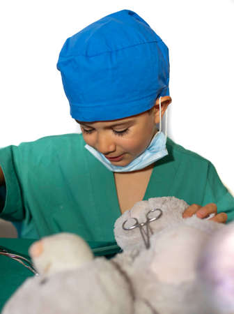 happy child disguised as a surgeon playing doctor operating on a teddy bearの写真素材