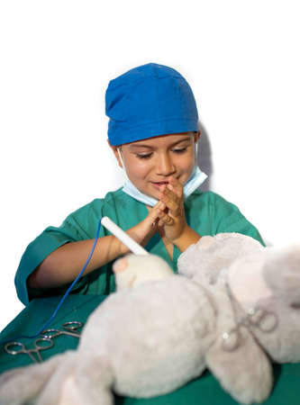 happy child disguised as a surgeon playing doctor operating on a teddy bearの写真素材