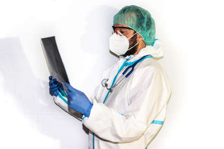 Middle-aged male doctor dressed in protective gear and stethoscope standing on an isolated white background facing the camera. Concerned person.の写真素材