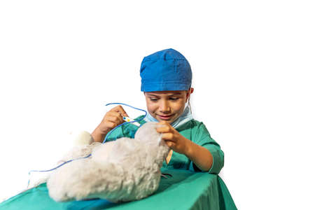 happy child disguised as a surgeon playing doctor operating on a teddy bearの写真素材