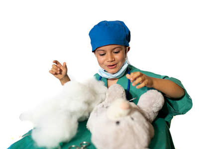 happy child disguised as a surgeon playing doctor operating on a teddy bearの写真素材