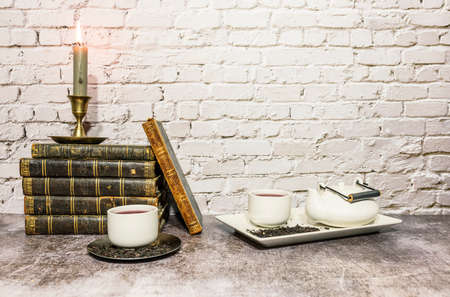 still life of antique books with candles and tea set, a clock is incorporatedの写真素材