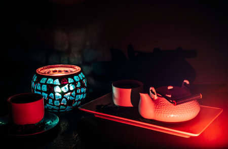 Tea set on dark background illuminated with dim light whit a candleの写真素材