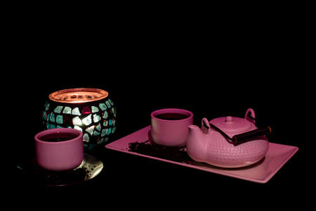 Tea set on dark background illuminated with dim light whit a candleの写真素材
