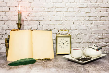 still life of antique books with candles and tea set, a clock is incorporatedの写真素材