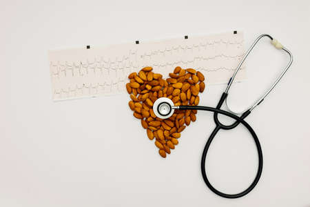 dark stethoscope with a heart made of almonds and an electrocardiogramの写真素材