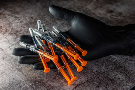 application of botox in pre-filled syringe in hand with black latex glovesの写真素材