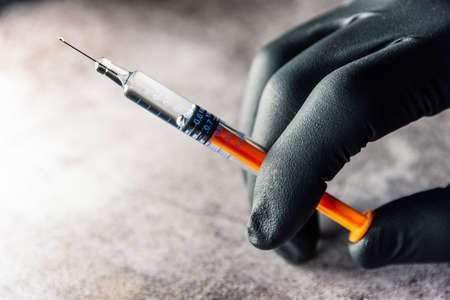 application of beauty treatment
 in pre-filled syringe in hand with black latex glovesの写真素材
