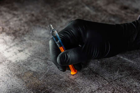 application of beauty treatment
 in pre-filled syringe in hand with black latex glovesの写真素材