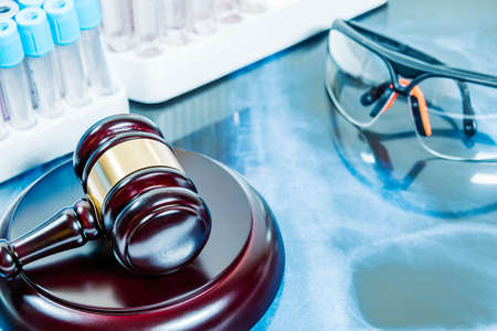 JUDGE'S MALLET ON MAGNETIC RESONANCE BACKGROUND TOGETHER WITH LABORATORY SAMPLES AND PROTECTIVE GLASSES. SELECTIVE FOCUS.の写真素材