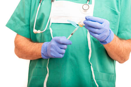 Male nurse carrying vaccine or medication in syringe with safety needle, dressed in green scrubs on white background.の写真素材