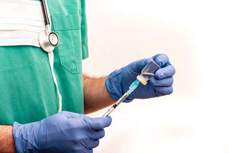 Male nurse carrying vaccine or medication in syringe with safety needle, dressed in green scrubs on white background.の写真素材