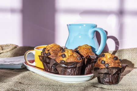Breakfast with milk and muffins served in a traditional teapot with a yellow and pink color palette.の写真素材