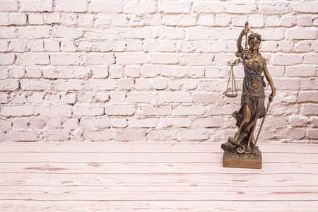 Statue symbol of justice on wooden floor and white brick wall.の写真素材