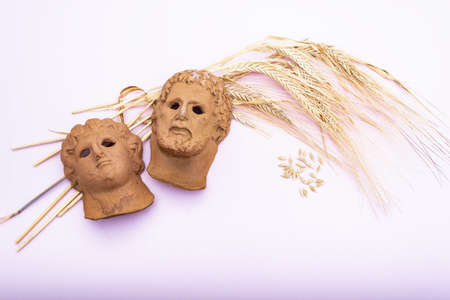 representation of a Roman god's head on a bouquet of dried wheat on a pink backgroundの写真素材