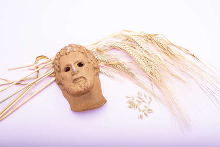 representation of a Roman god's head on a bouquet of dried wheat on a pink backgroundの写真素材