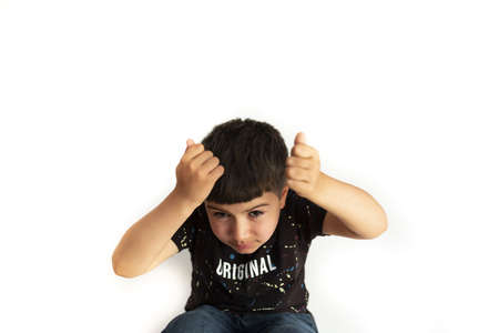 Caucasian boy expressing surprise at object falling on him with arms on his head on white backgroundの写真素材