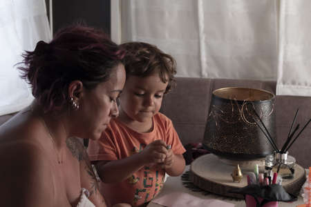 Mother and 3-year-old Caucasian son make crafts in caravan while on vacationの写真素材