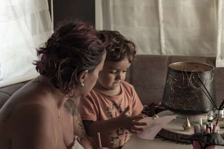 Mother and 3-year-old Caucasian son make crafts in caravan while on vacationの写真素材