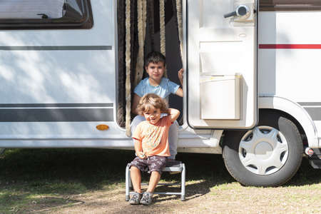 two Caucasian children play and spend alternative holidays in a caravanの写真素材