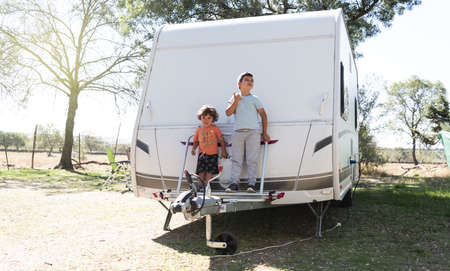 two Caucasian children play and spend alternative holidays in a caravanの写真素材