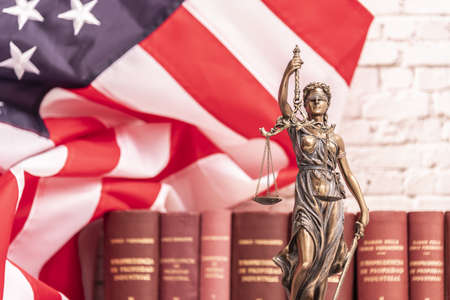 The statue of justice Themis or Iustitia, the blindfolded goddess of justice against a flag of the United States of America, as a legal concept.の写真素材
