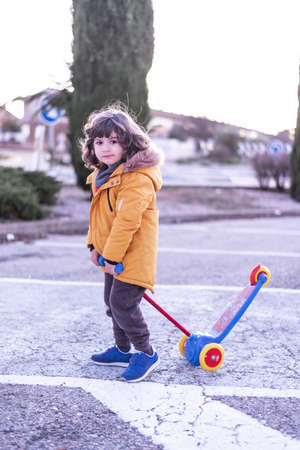 5 year old Caucasian boy rides scooter.の写真素材