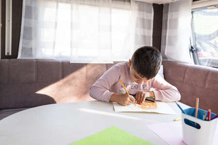 6-year-old Caucasian boy paints inside caravan on weekend trip.の写真素材