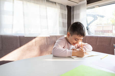 6-year-old Caucasian boy paints inside caravan on weekend trip.の写真素材