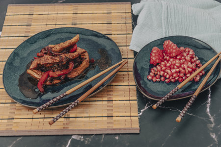 Chicken strips with red pepper in teriyaki sauce served with pomegranate seeds for dessert.