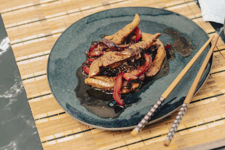 Chicken strips with red pepper in teriyaki sauce served.の写真素材